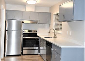 A kitchen with stainless steel appliances and white counter tops